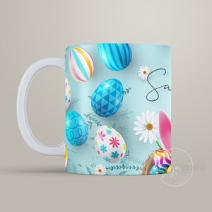 May include: A white ceramic mug with a blue background and a pattern of colorful Easter eggs and flowers. The text "Sa" is visible on the mug.