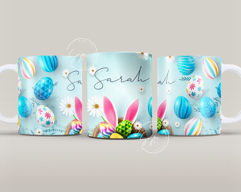 May include: White ceramic mug with a blue background and a design of colorful Easter eggs, bunny ears, and flowers. The mug has the name "Sarah" written on it.