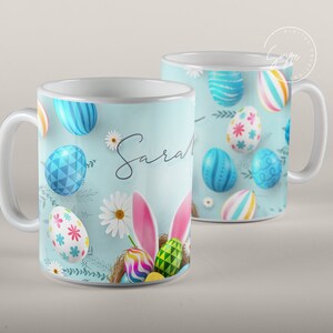 May include: White ceramic mug with a blue and white Easter egg design. The mug has a handle and the name "Sarah" written on it.