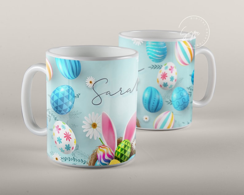 May include: White ceramic mug with a blue and white Easter egg design. The mug has a handle and the name "Sarah" written on it.