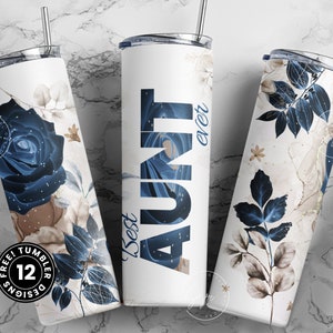 May include: Three stainless steel tumblers with different designs. The first tumbler has a blue rose with brown and white floral accents. The second tumbler has a blue and white abstract design with the text "Best Aunt ever". The third tumbler has a blue and white floral design with brown accents.
