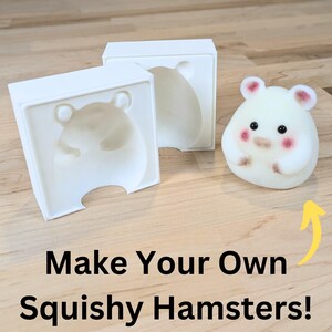 May include: Two white plastic moulds for making squishy hamster toys. The moulds are open and show the shape of a hamster. A small, white, fuzzy hamster toy is sitting on a wooden surface next to the moulds. The text "Make Your Own Squishy Hamsters!" is written below the image.