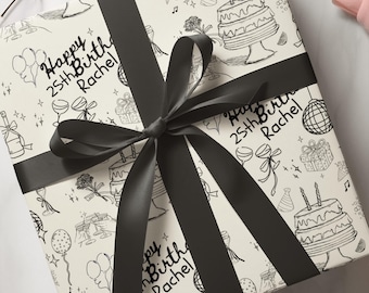 Pode incluir: Papel de embrulho branco com uma fita preta. O papel tem um padrão repetido de rabiscos de festa de aniversário, incluindo balões, bolo e taças de champanhe. O texto "Happy 25th Birth Rachel" está escrito no papel.