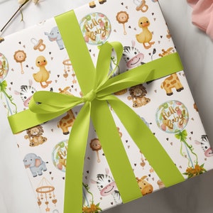 May include: A white gift box with a green ribbon tied in a bow. The box is wrapped in paper with a pattern of baby animals, including a zebra, giraffe, elephant, and lion. The paper also features a balloon with the words "Hello Baby" on it.