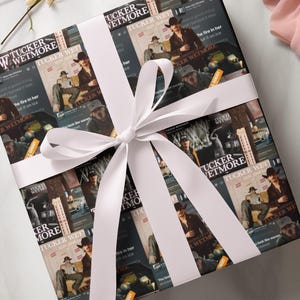 May include: A white gift box wrapped in a collage of images featuring a country music artist. The box is tied with a white satin ribbon and bow. The images feature the artist's name "Tucker Wetmore" and the text "2024 Tour Dates".