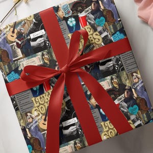 May include: A red and white gift box wrapped in a collage of Luke Combs album covers, concert tickets, and photos. The box is tied with a red satin ribbon.