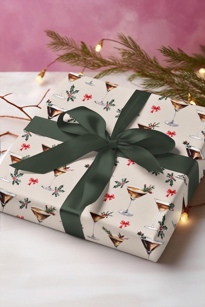 K&ouml;nnte beinhalten: Eine wei&szlig;e Geschenkbox mit einem gr&uuml;nen Band und einem Muster aus braunen Martini-Gl&auml;sern mit Stechpalme und roten Schleifen.
