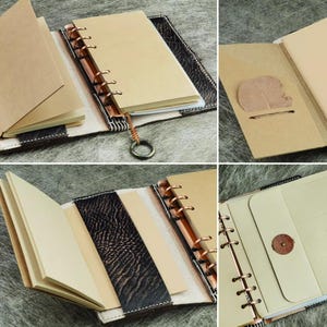 Pu&ograve; includere: Un diario rilegato in pelle con un raccoglitore ad anelli color rame. Il diario ha una copertina marrone e nera, con pagine color crema e una tasca a forma di foglia. Il diario &egrave; aperto, rivelando le pagine e il meccanismo di rilegatura.