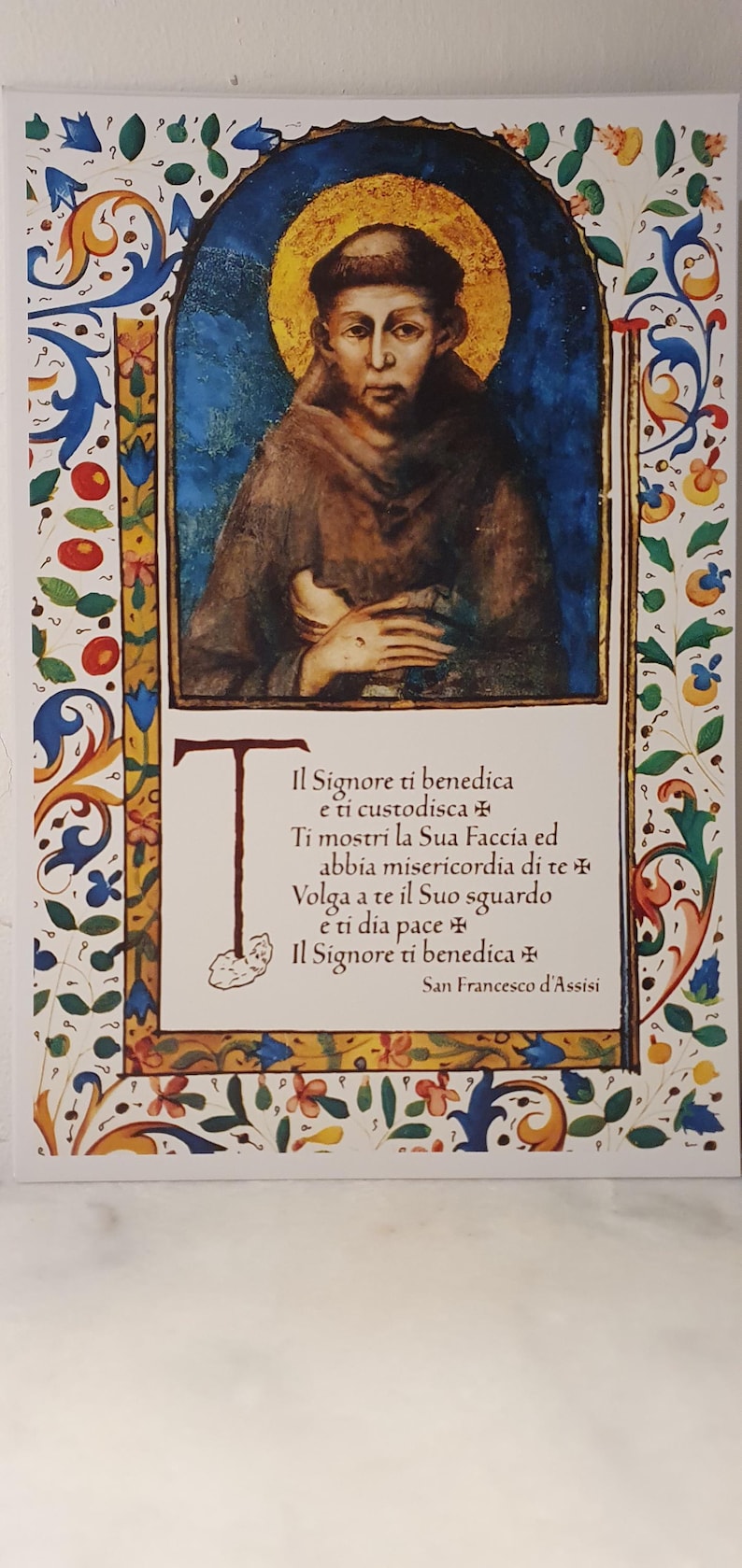 K&ouml;nnte beinhalten: Ein religi&ouml;ser Kunstdruck mit einem Portr&auml;t eines Mannes mit Heiligenschein, umrahmt von einem verzierten Blumenrand. Der Druck enth&auml;lt italienischen Text von San Francesco d'Assisi.