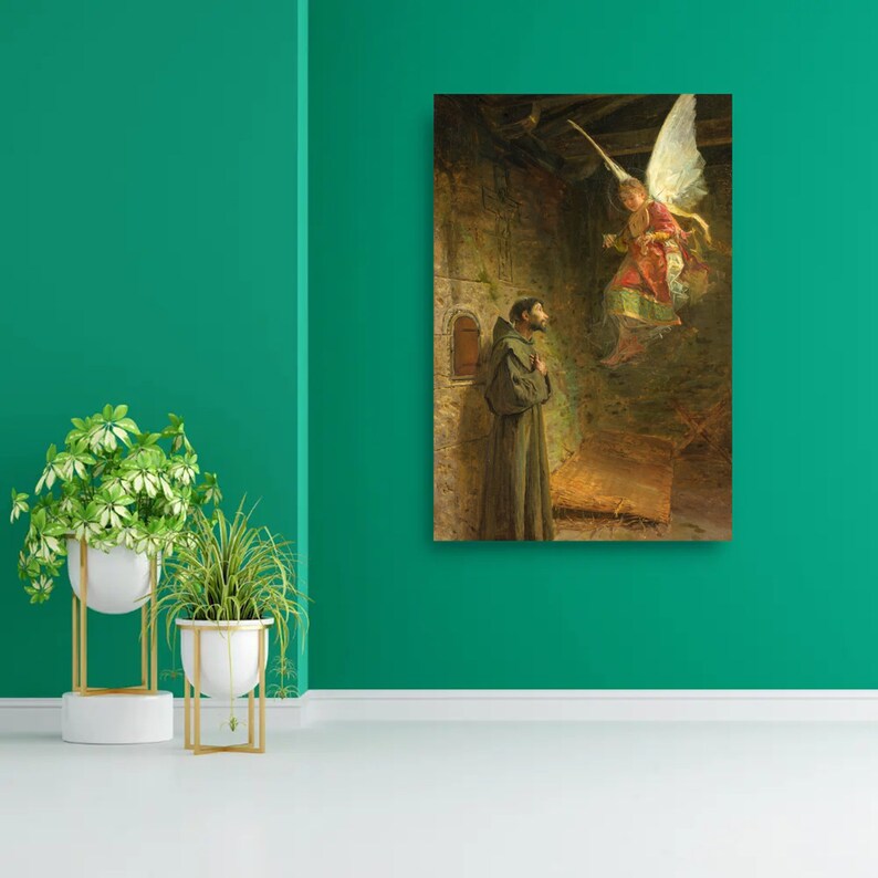 May include: A framed print of a religious painting depicting a man in a brown robe looking up at an angel with white wings. The angel is wearing a red and gold garment. The background is a stone structure with a small window.