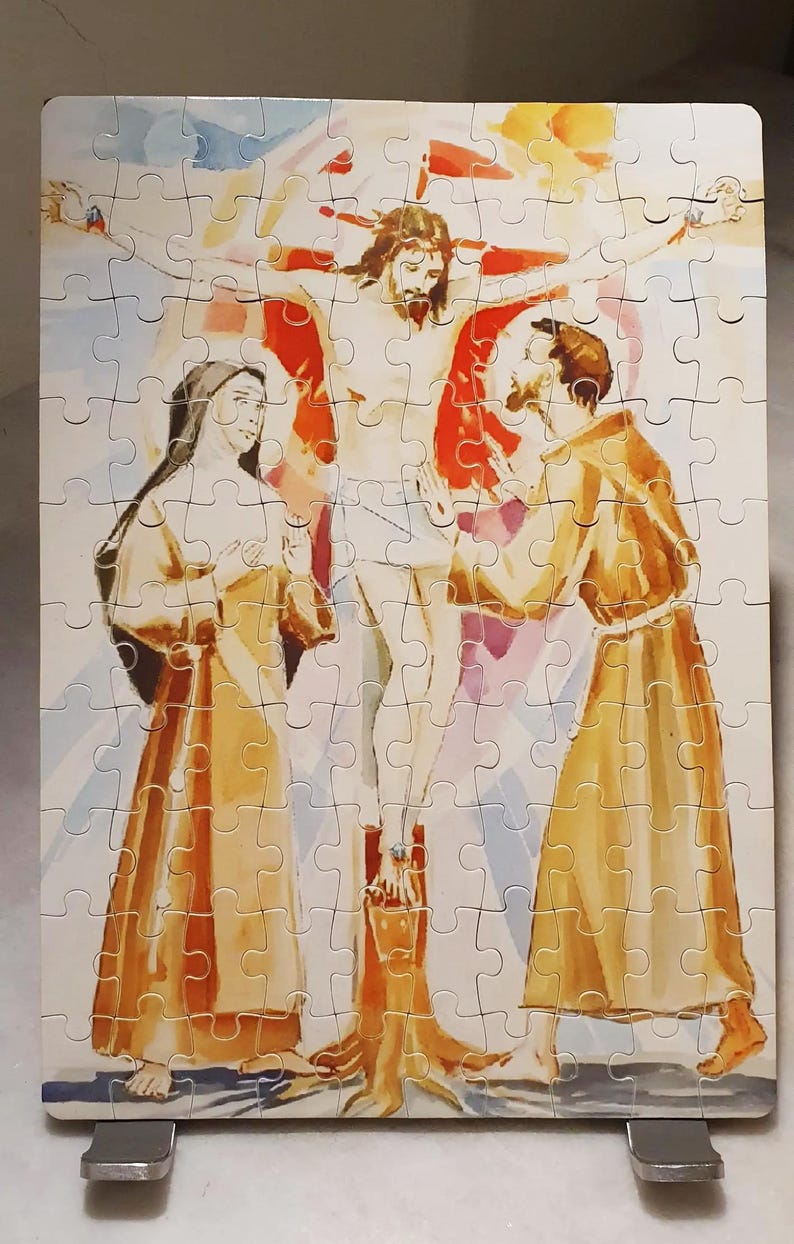 May include: A completed jigsaw puzzle depicting a religious scene. The image shows a figure on a cross with two other figures in robes. The puzzle pieces are interlocked, forming a complete picture with a light background.