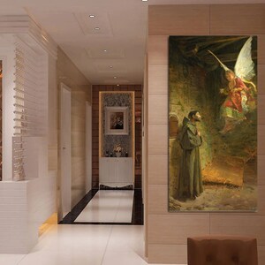 May include: A vertical canvas print of a religious scene. An angel with large white wings descends towards a man in a brown robe. The background is a stone structure with warm lighting.
