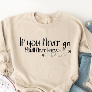 May include: A beige sweatshirt with the text "If you never go you'll never know" and a small airplane graphic.