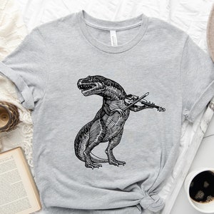 May include: A gray t-shirt with a black and white illustration of a dinosaur playing the violin.