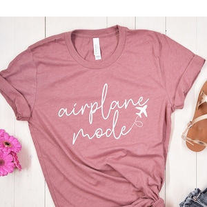 May include: A mauve t-shirt with the text "airplane mode" in white cursive lettering and a small airplane icon.
