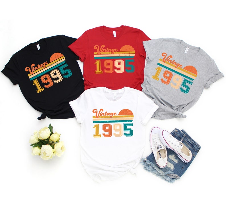May include: A collection of t-shirts in black, red, white, and gray, each featuring a retro design with the text "Vintage 1995" and a sunset graphic. The shirts are casual wear, suitable for everyday use.