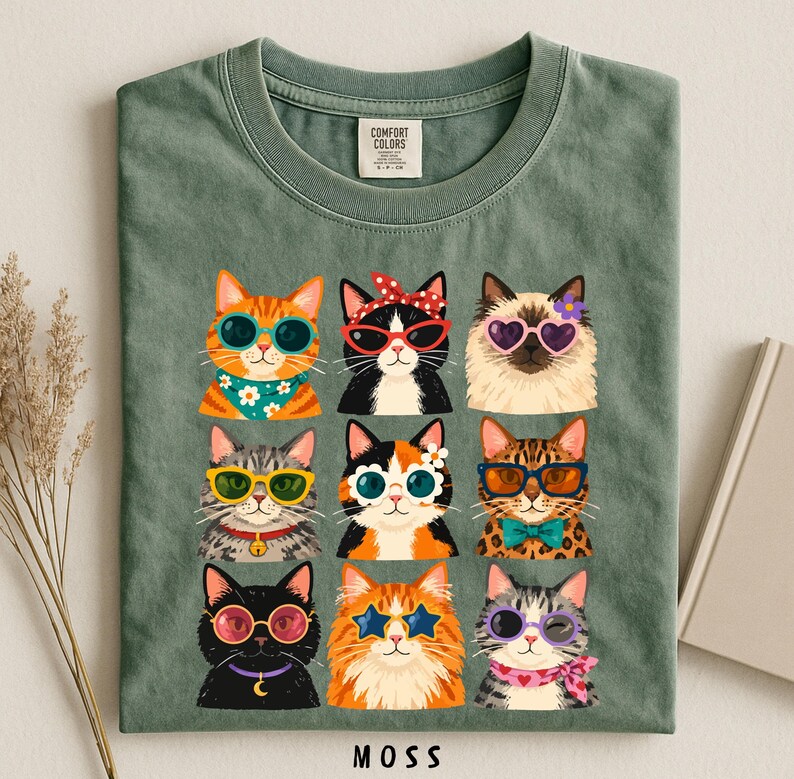 A green t-shirt with a collage of nine cat illustrations wearing sunglasses and accessories, arranged in a grid pattern.