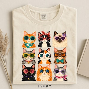 A t-shirt with a collage of nine cat illustrations wearing sunglasses and accessories, arranged in a 3x3 grid.