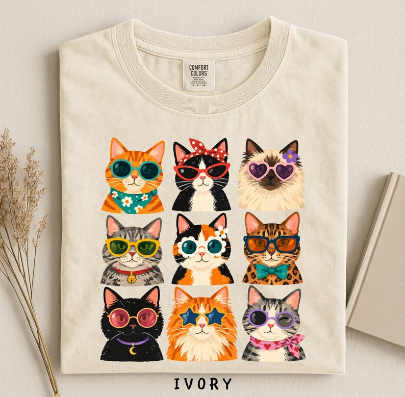 A t-shirt with a collage of nine cat illustrations wearing sunglasses and accessories, arranged in a 3x3 grid.