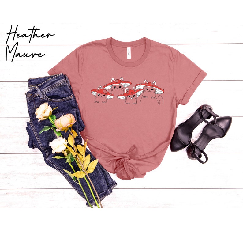 May include: A heather mauve t-shirt with a graphic of four cats wearing red mushroom hats. The cats have different expressions and the text "meow meow" is written below them.