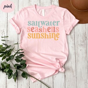 a pink shirt that says, saltwater seashells sunshine