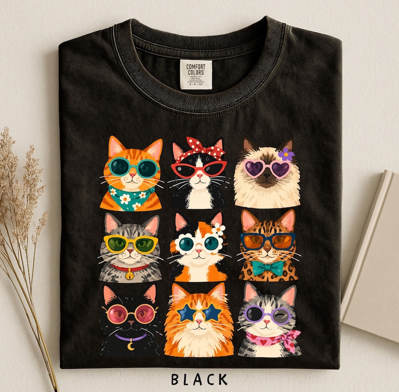 A black t-shirt with a collage of nine cat illustrations wearing sunglasses and accessories, arranged in a 3x3 grid.