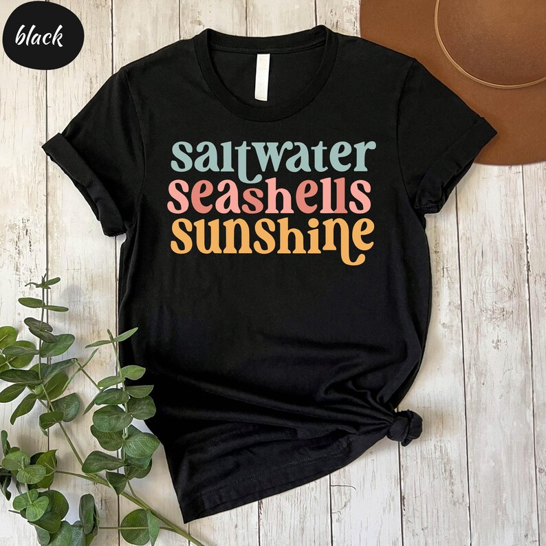a black t - shirt that says saltwater seashells sunshine