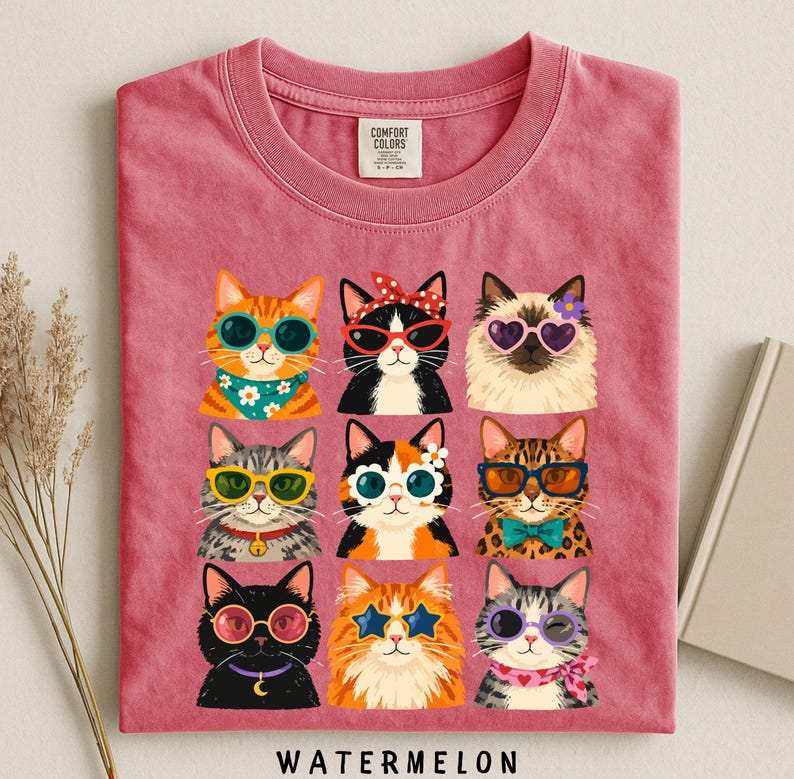 A pink t-shirt with a collage of nine cat illustrations wearing sunglasses and accessories, arranged in a 3x3 grid.