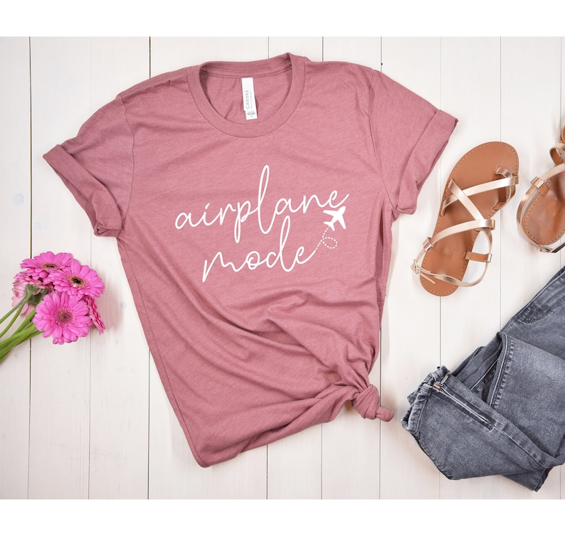 May include: A mauve t-shirt with the text "airplane mode" in white cursive lettering and a small airplane icon.
