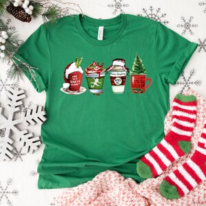 Puede incluir: Camiseta verde con un dise&ntilde;o navide&ntilde;o con cuatro tazas con bebidas festivas y el texto "Are you serious, Clark?"  "Merry Christmas" y "Little bit of sap".