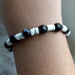 Puede incluir: Un brazalete de cuentas negras y blancas con cuentas negras facetadas que se alternan con cuentas espaciadoras blancas.