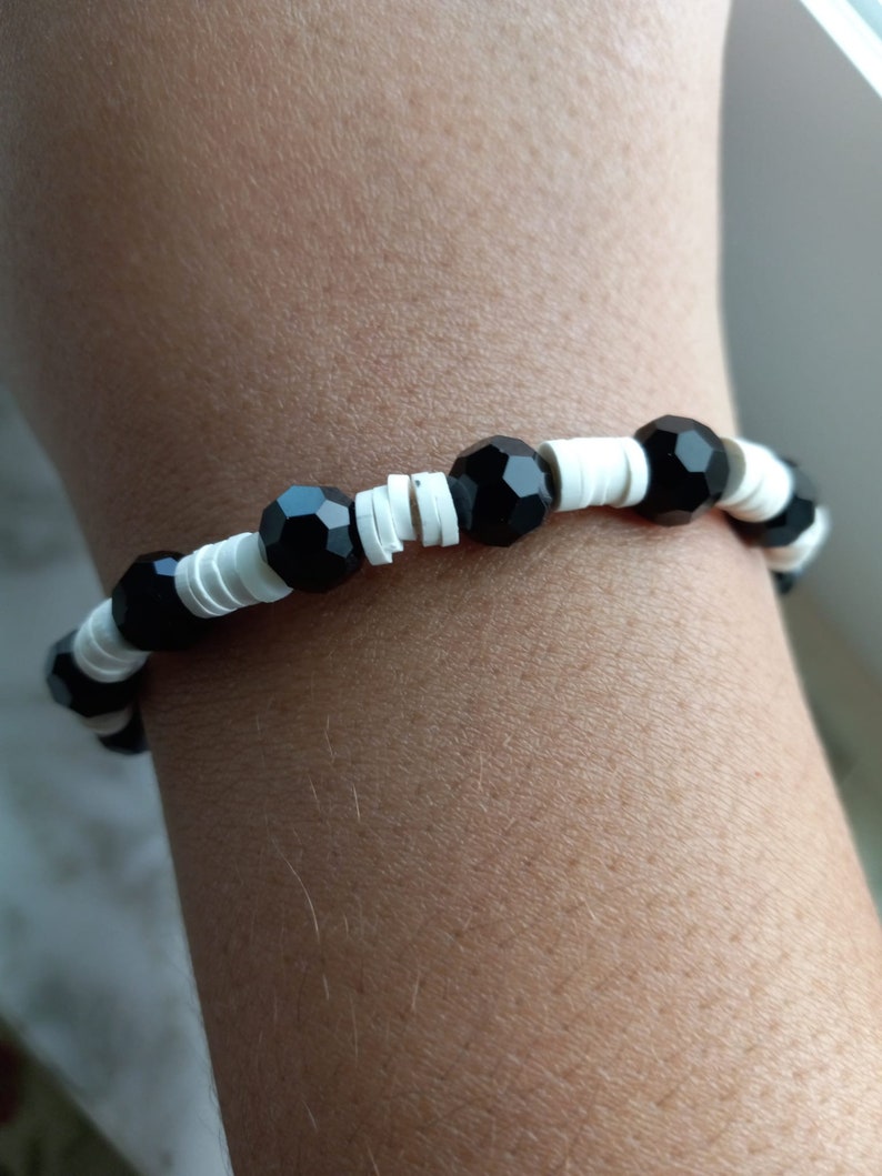 Puede incluir: Un brazalete de cuentas negras y blancas con cuentas negras facetadas que se alternan con cuentas espaciadoras blancas.