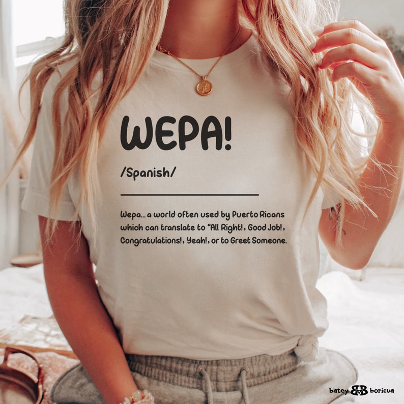 K&ouml;nnte beinhalten: Wei&szlig;es T-Shirt mit dem Wort "WEPA!" in schwarzer Schrift und der Definition des Wortes auf Spanisch. Die Definition lautet: "Wepa... ein Wort, das oft von Puertoricanern verwendet wird und sich &uuml;bersetzen l&auml;sst mit "Alles klar!, Gut gemacht!, Gl&uuml;ckwunsch!, Ja!, oder um jemanden zu gr&uuml;&szlig;en."