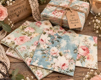 May include: A stack of square paper napkins featuring a blue background with a pink and white floral pattern, tied with twine and a brown paper tag that reads Made for Beautiful Moments. The napkins are arranged on a wooden surface.