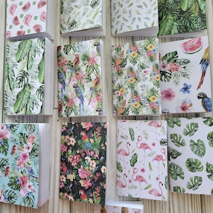 May include: A collection of 12 small notebooks with various tropical-themed patterns. The covers feature designs of pineapples, flamingos, parrots, palm leaves, watermelon, and flowers.