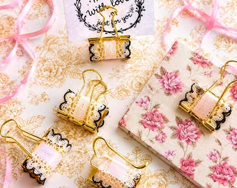May include: Gold metal binder clips decorated with pale pink ribbon and black-edged white lace trim. One clip holds a white rectangular card featuring a black floral wreath design and the text "made with love just for you" in cursive script.