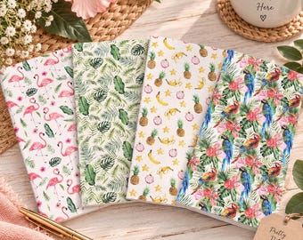 May include: Four rectangular notebooks with distinct tropical patterns: one with pink flamingos, one with green palm leaves, one with yellow pineapples and bananas, and one with colorful parrots and hibiscus flowers, arranged on a wooden surface.