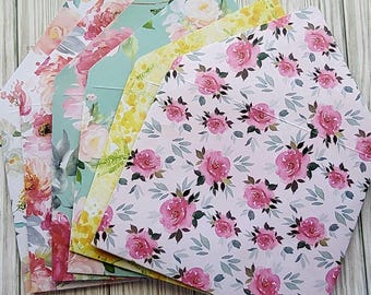 May include: A stack of floral patterned envelopes in various colors, including pink, yellow, green, and blue. The envelopes are all decorated with watercolor-style floral designs.