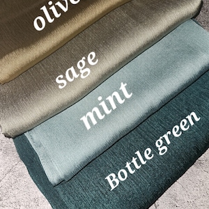 May include: Four fabric swatches in different shades of green: olive, sage, mint, and bottle green. The swatches are folded on top of each other, with the darkest shade on the bottom and the lightest shade on top.