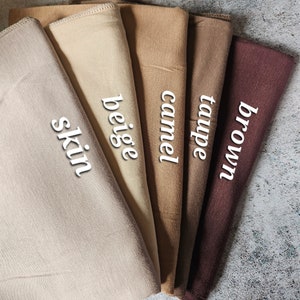 K&ouml;nnte beinhalten: F&uuml;nf Stoffmuster in verschiedenen Braunt&ouml;nen, von hell bis dunkel. Die Muster sind mit "Haut", "Beige", "Camel", "Taupe" und "Braun" beschriftet.