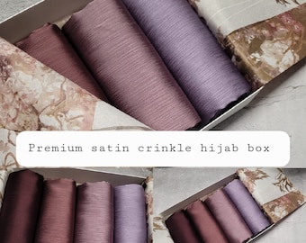 May include: A box filled with six satin crinkle hijabs in shades of purple and burgundy. The box is lined with a floral patterned fabric.  Premium satin crinkle hijab box.