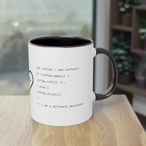 Könnte beinhalten: Eine weiße Kaffeetasse mit schwarzem Rand und Henkel. Die Tasse zeigt einen Codeausschnitt mit dem Text "var coffee = new coffee() if (coffee.empty) { coffee.refill(); } else { coffee.drink(); } // I am a software developer"