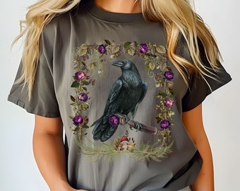 May include: A dark gray t-shirt with a graphic print of a black raven perched on a branch surrounded by purple roses and green leaves. The text "PEPPER" is visible in the bottom right corner of the image.