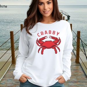 May include: White long-sleeved sweatshirt with a red crab illustration and the word "CRABBY" printed on the front.
