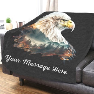 May include: A black fleece throw blanket with a printed image of an eagle with a mountain landscape superimposed on its feathers. The text "Your Message Here" is printed on the blanket.