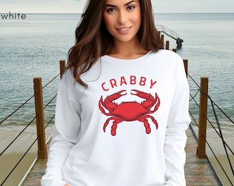 May include: White long-sleeved sweatshirt with a red crab illustration and the word "CRABBY" printed on the front.