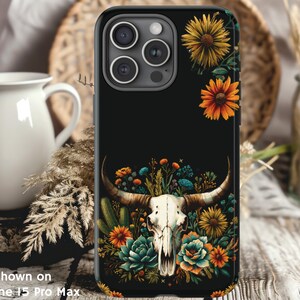 May include: Black phone case with a floral design featuring a skull with antlers, flowers, and leaves. The phone case is shown on an iPhone 13 Pro Max.