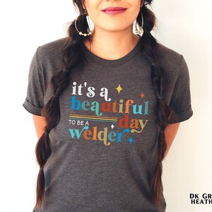 May include: Dark grey heather t-shirt with the text "it's a beautiful day to be a welder" in colorful letters with stars and stripes.