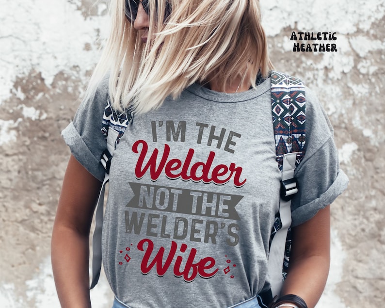 K&ouml;nnte beinhalten: Graues T-Shirt mit dem Text "I'm the Welder not the Welder's Wife" in rot und grau.