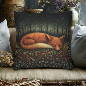May include: Decorative square pillow featuring a sleeping fox in a forest scene. The pillow has a dark background with a starry night sky and a row of trees. The fox is orange with a white-tipped tail, resting on a bed of leaves.